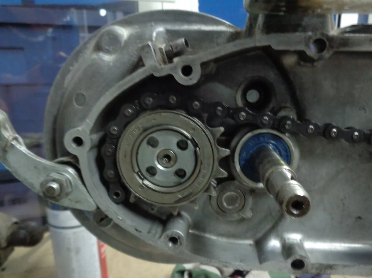 detalle del paso de la cadena de un vespino por el piñón de bici en dirección a la otra punta de la cadena