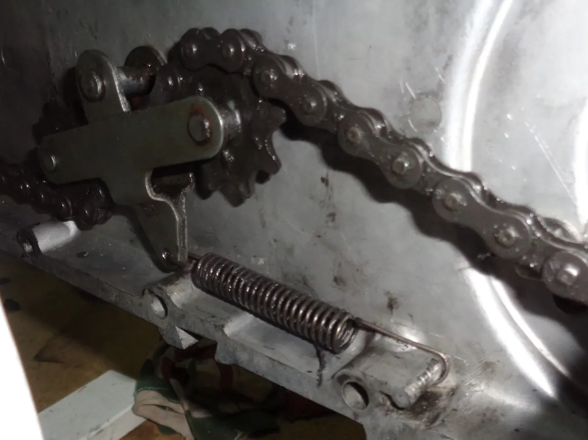 Muelle de tensor de cadena de vespino montado en el carter de un vespino en proceso de restauración del motor