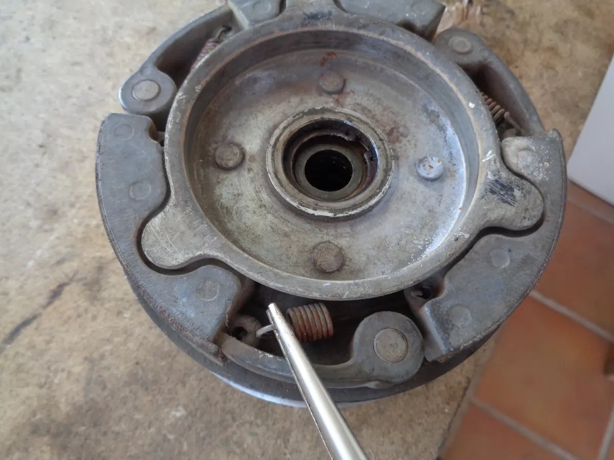 Zapatas de embrague de vespino en el embrague, mostrando como un alicate de punta fina retira uno de los muelles