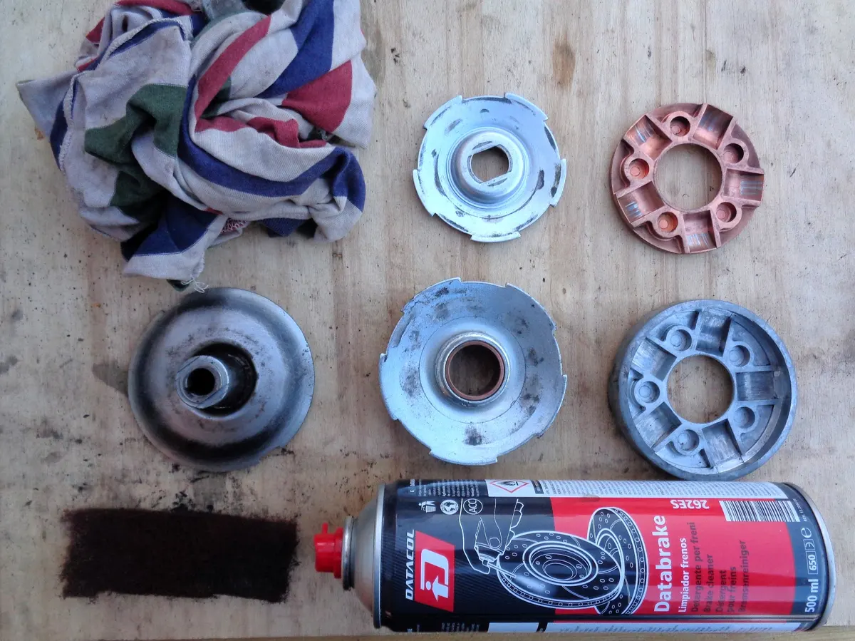 Variador de Vespino desmontado sobre una mesa con limpiafrenos, estropajo y trapo para proceder a limpiarlos