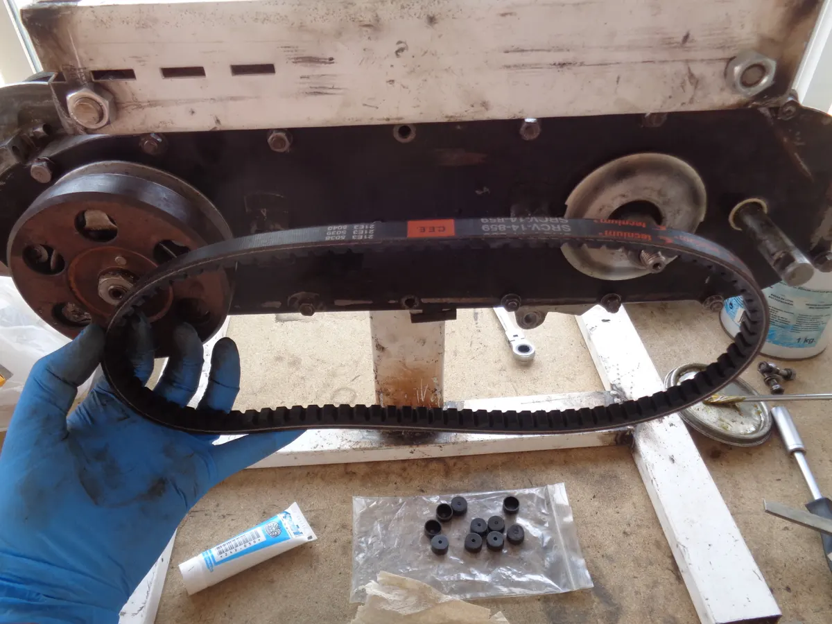Correa dentada de variador junto a un motor de vespino en proceso de montaje