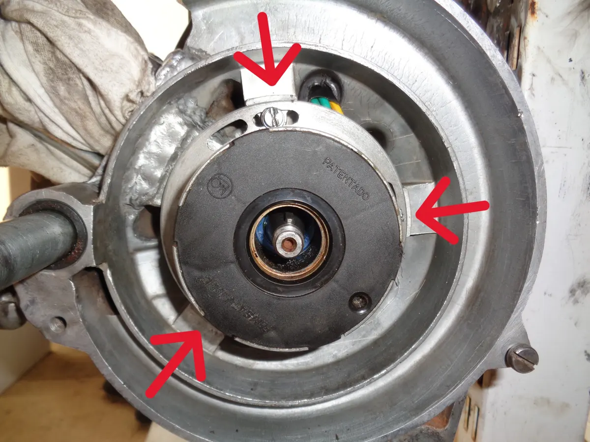 detalle de los 3 tornillos que fijan el estator al carter de un vespino señalados con flechas en el carter