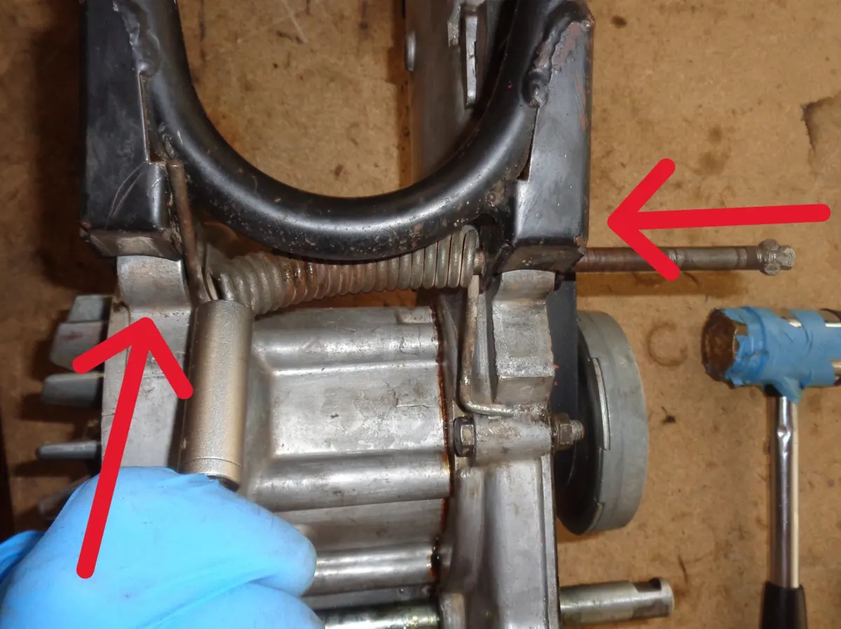 Ilustración con flechas de la introduccion del eje del caballete central de un vespino a través del muelle