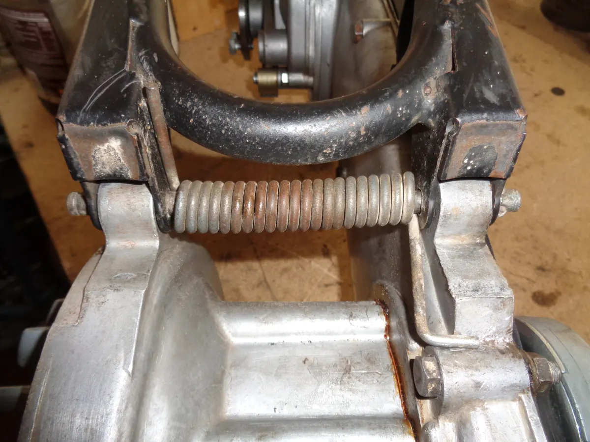 vista inferior del caballete central de vespino correctamente montado con su muelle y eje correspondiente.