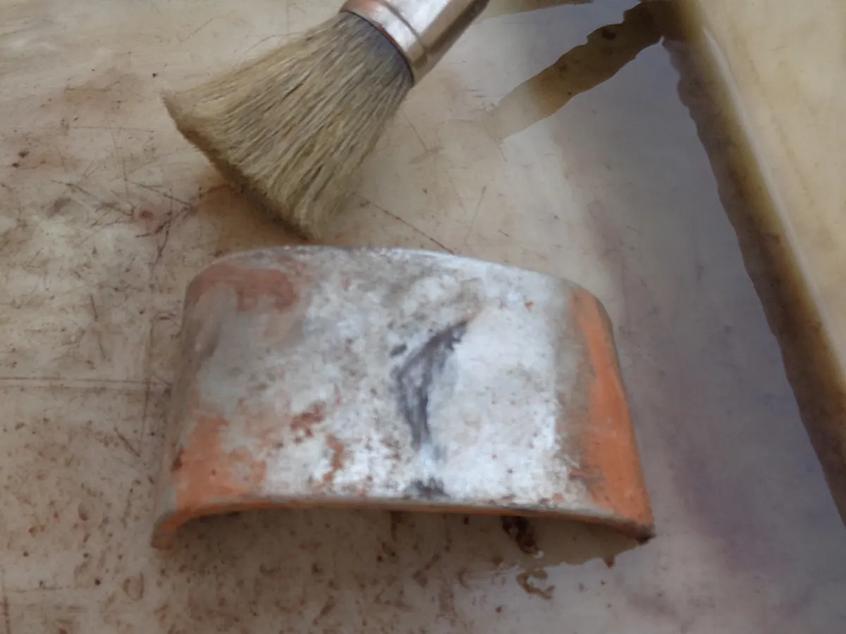 deflector de cilindro de vespino sucio junto a una brocha y gasolina para su limpieza