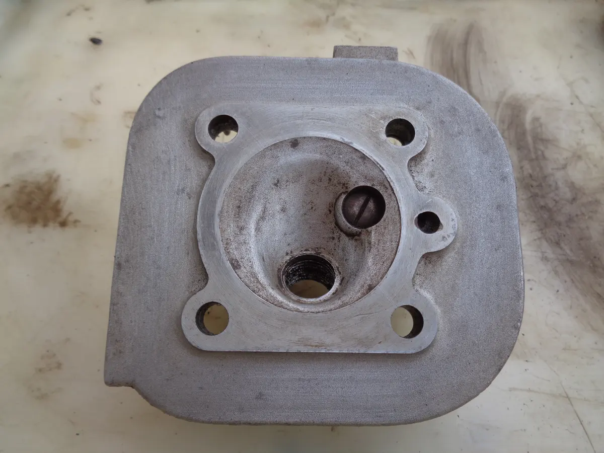 vista de la cámara de compresión de la culata de un vespino desmontada y sobre la mesa