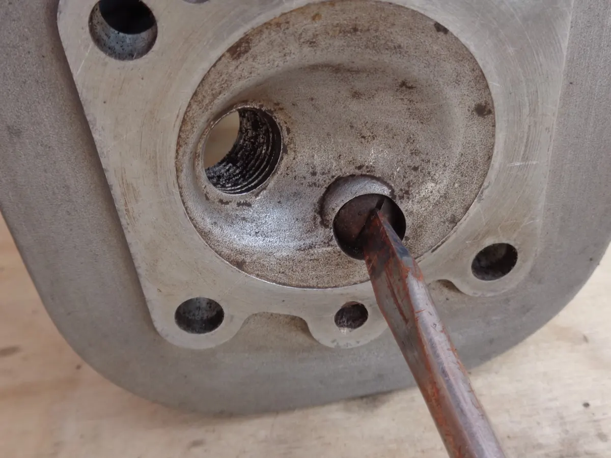 destornillador en cabeza de válvula de descompresor de culata de vespino en proceso de desmontaje