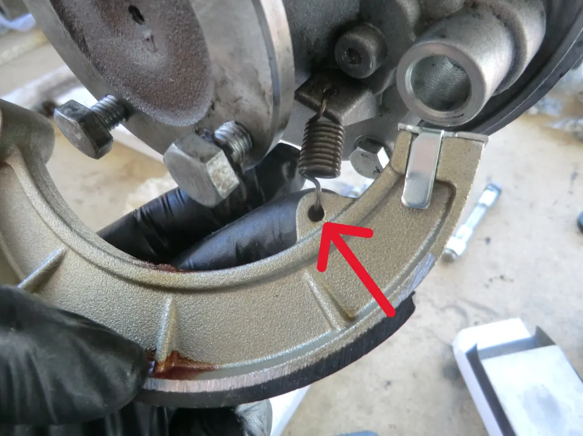 Detalle del enganche del muelle del freno trasero del vespino con la zapata de freno previo a montarla en su posición en el motor de un vespino