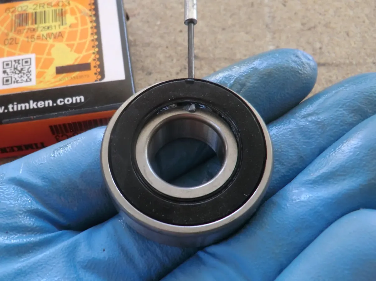 Rodamiento de cigüeñal de Vespino sellado al que se le está retirando con un destornillador de punta fina , el sello para que se engrase al funcionar