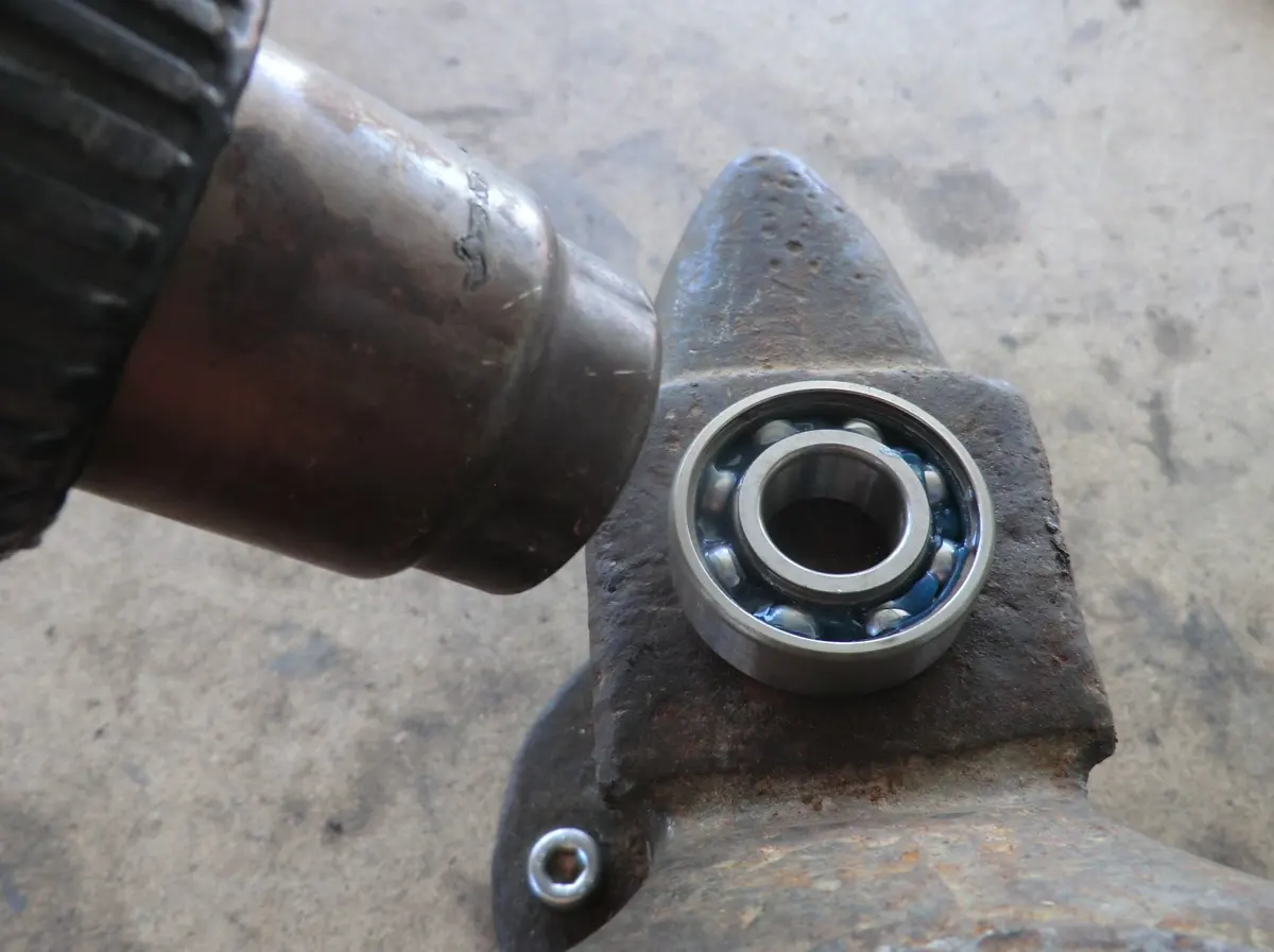 Detalle del calentamiento de un rodamiento de cigüeñal de vespino siendo calentado por una pistola de calor para que dilate y facilite su montaje