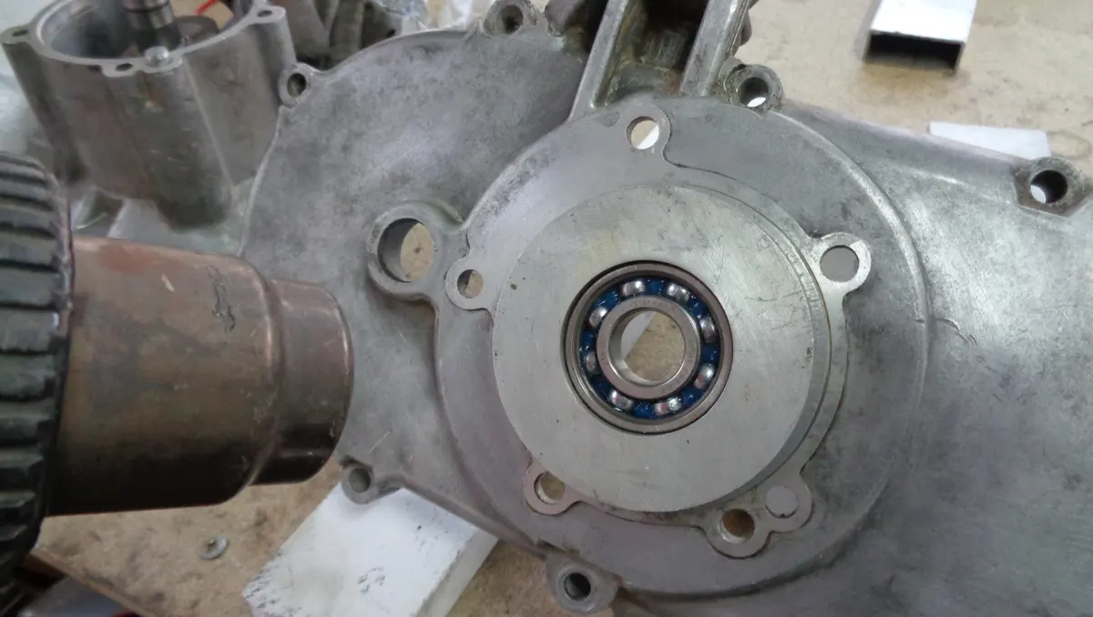 Pistola de calor calentando carter de vespino con rodamiento mostrando como calentarlo sin quemar la mesa, dadole cierta inclinación con respecto a esta