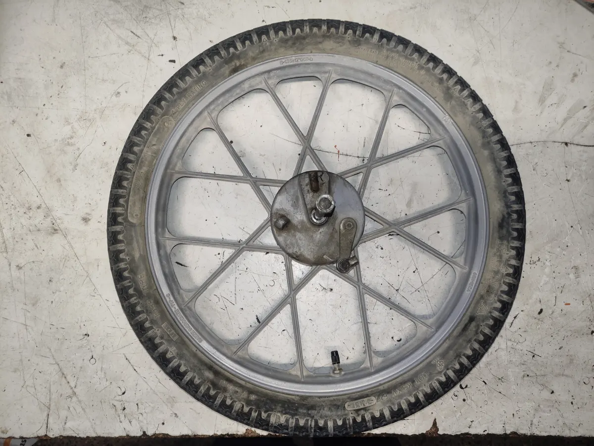 Rueda delantera de Vespino SC para restaurar, sucia y con el neumático viejo y agrietado