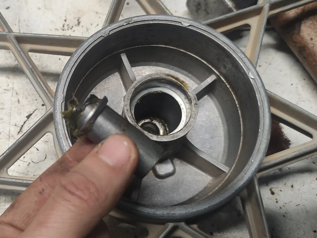 Detalle de la extracción con la mano del separador de rodamientos  del eje de la rueda delantera del vespino