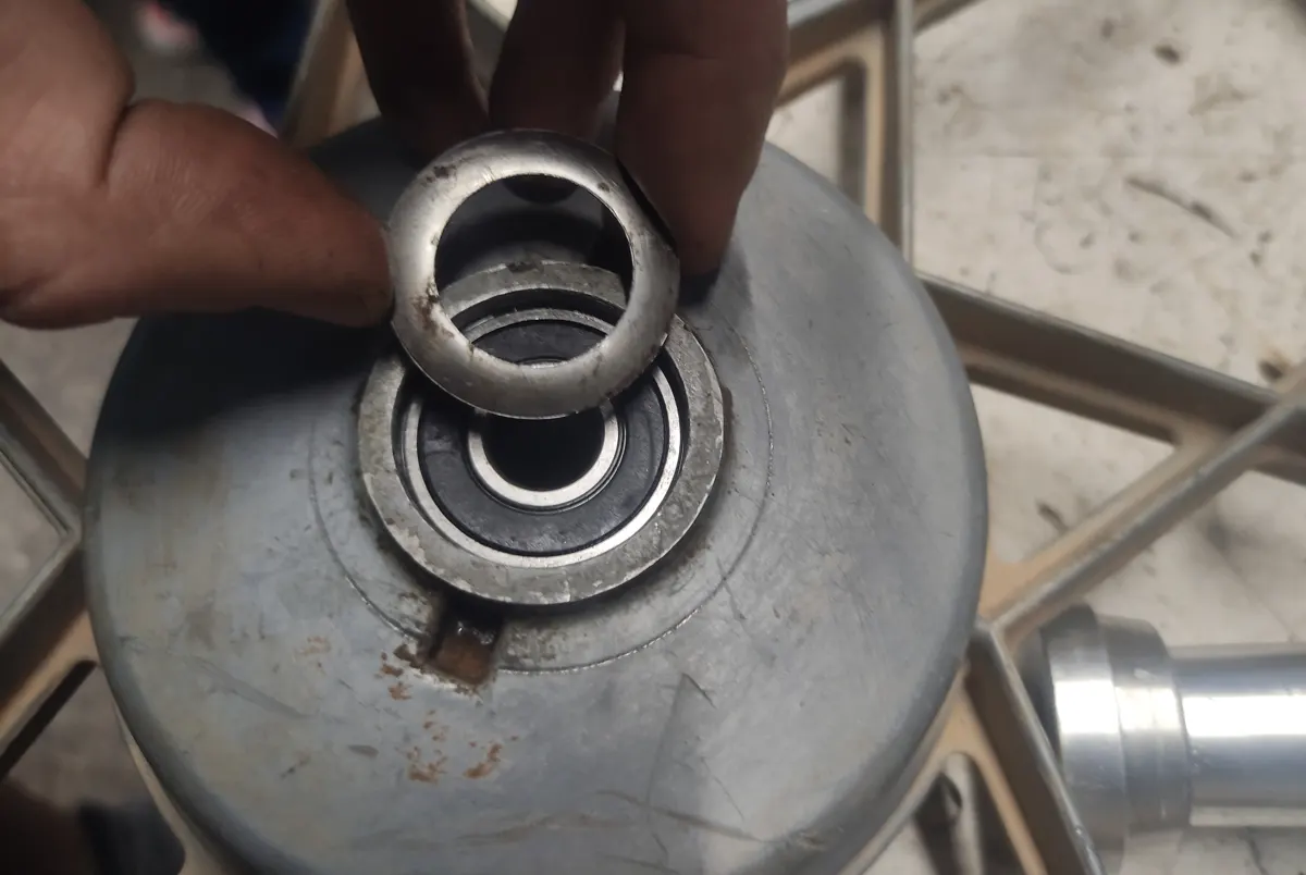 Detalle del guardapolvos de la rueda delantera de un vespino siendo colocado con por una mano en su alojamiento