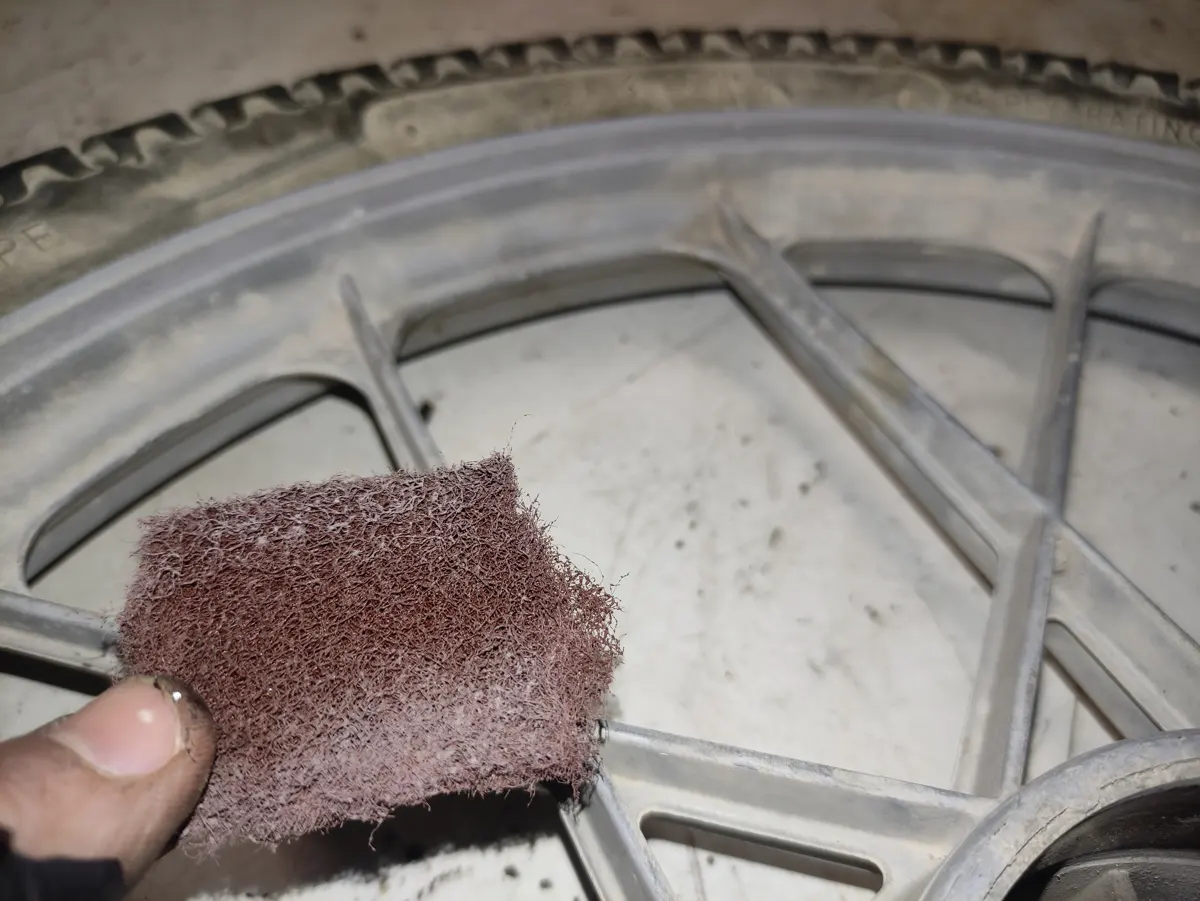 Limpieza de una llanta de vespino con estropajo para eliminar la mugre incrustada en la llanta.