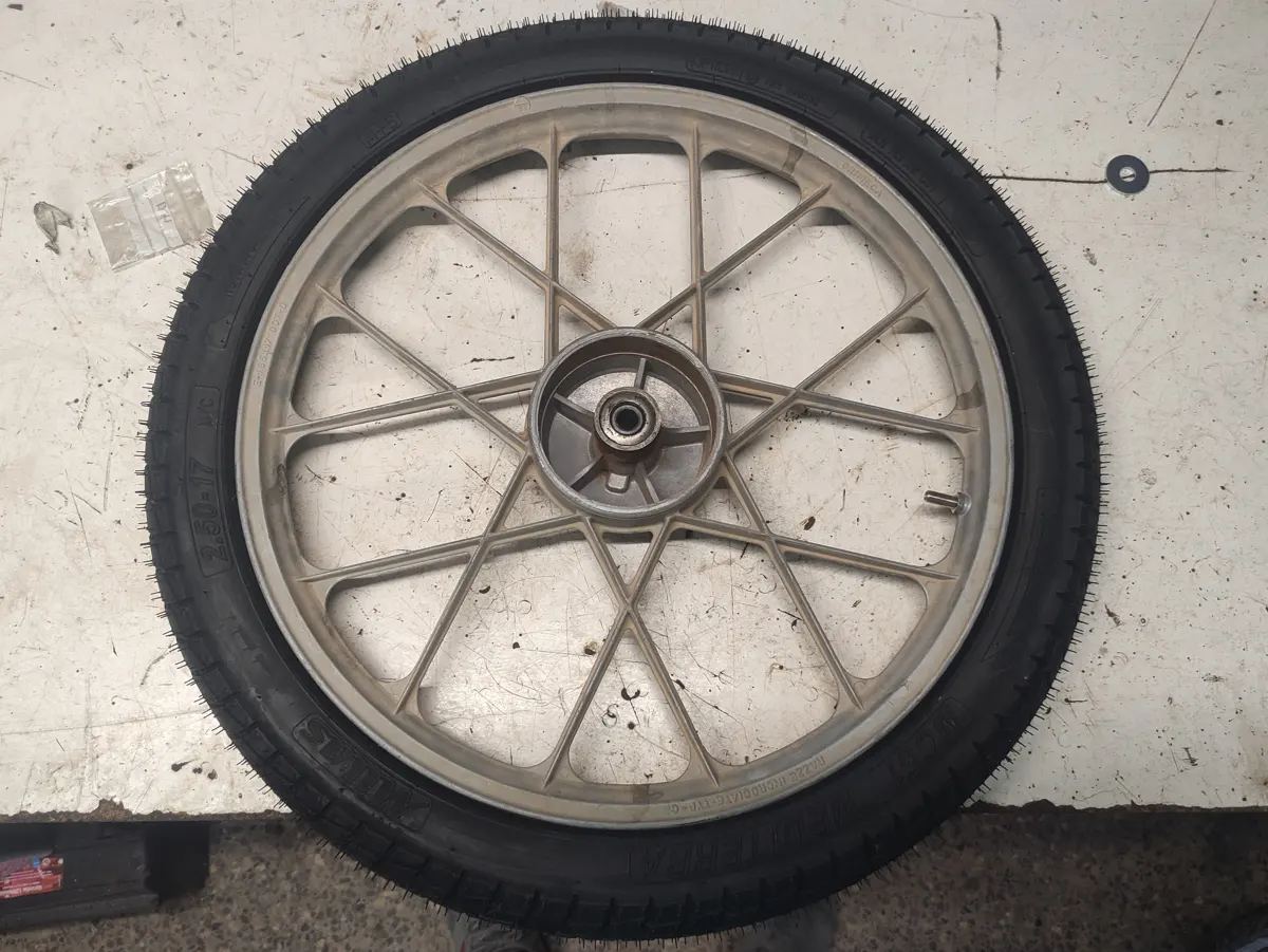 Rueda delantera de Vespino SC sobre una mesa con el neumático nuevo, previo a reemplazar rodamientos