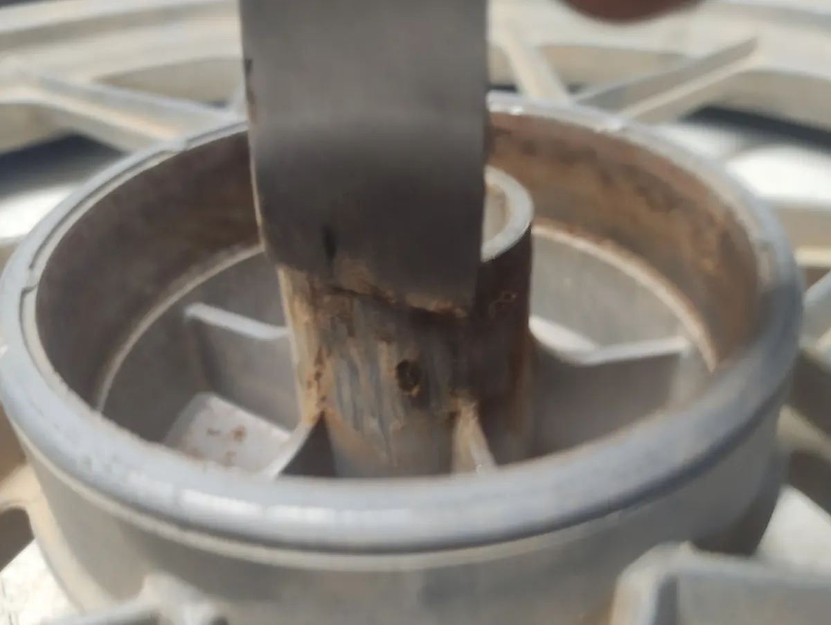 Proceso de limpieza del interior del buje de una llanta delantera de vespino con una espátula