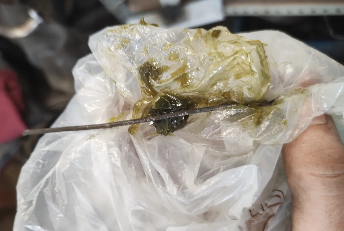 Bolsa de plástico con grasa de litio y un cable de moto siendo engrasado