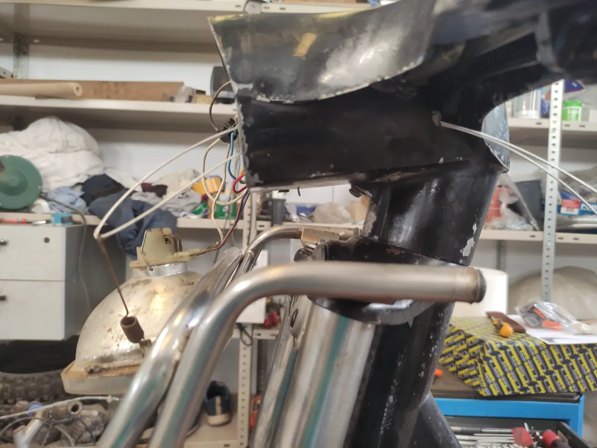 Detalle del proceso de montaje del faro de un vespino en el manillar, mostrando el cable atravesando el manillar y anclando en el muelle