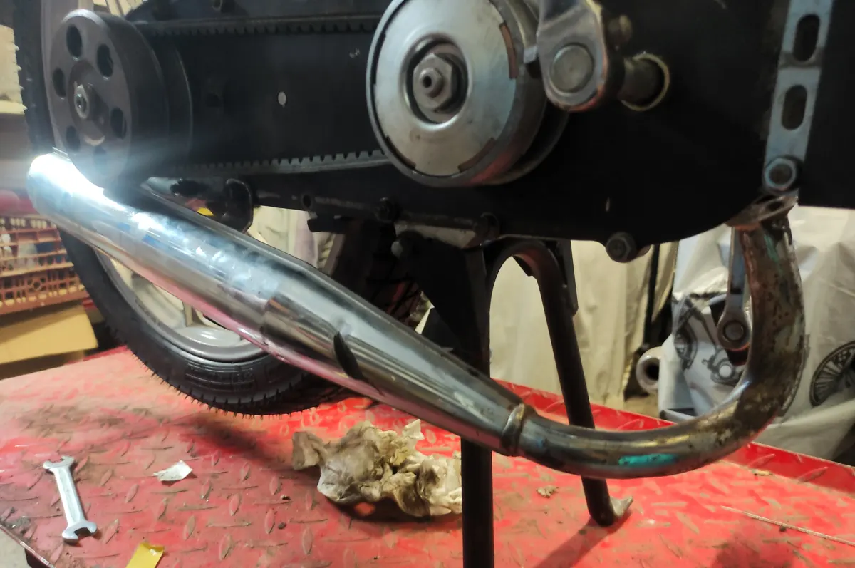 Proceso de montaje del escape de un vespino fijando el tornillo trasero para facilitar su montaje en el colector de escape