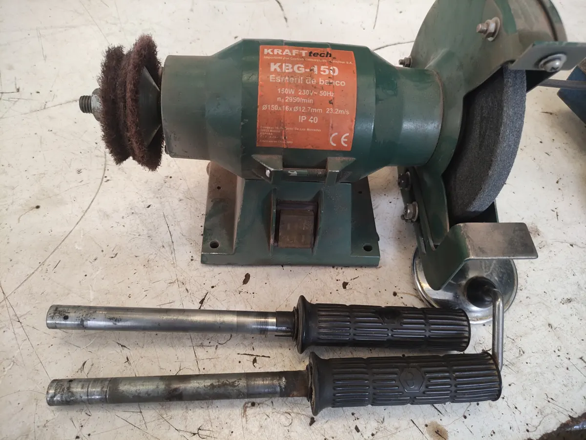 Mandos de vespino desmontados sobre una mesa junto a una pulidora para la limpieza de los ejes