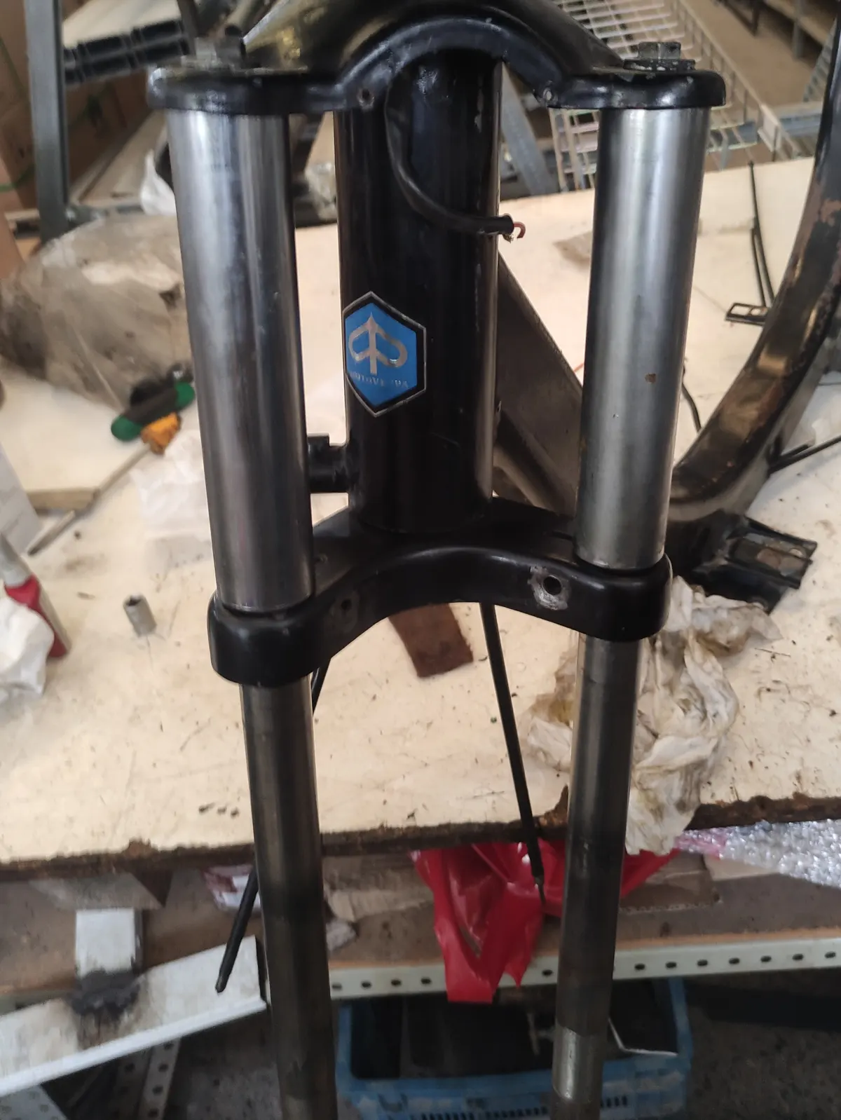 Suspensión delantera de vespino a medio montar sin muelles ni botellas, con el vespino sobre una mesa en proceso de montaje