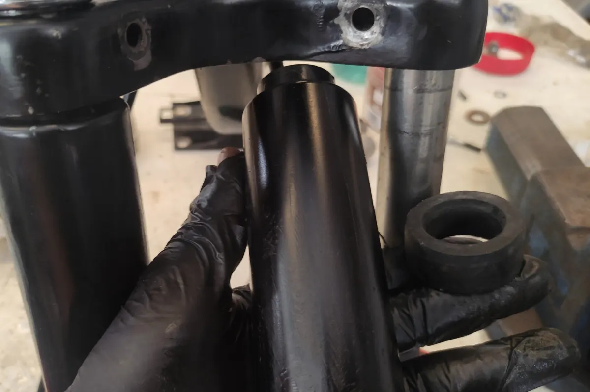 detalle del embellecedor inferior de la suspensión de un vespino junto con la goma frente a la tija y barras de suspensión del mismo