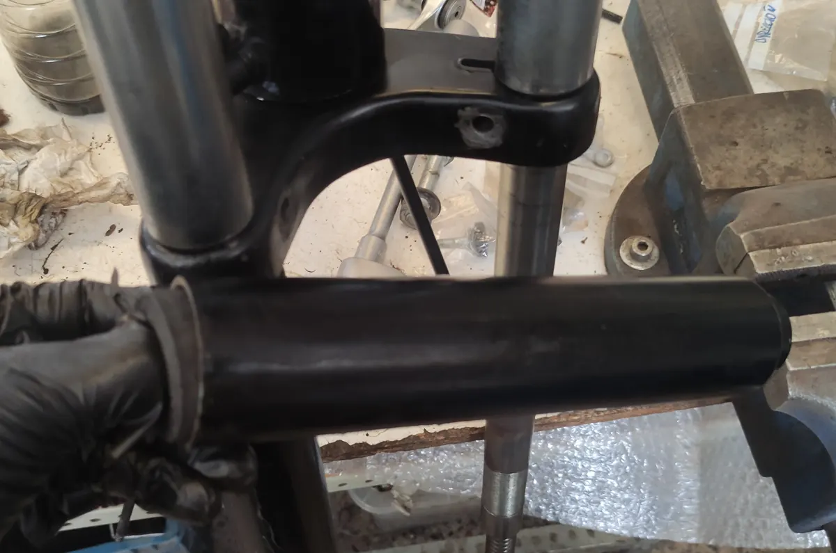 detalle del montaje de la goma del embellecedor inferior de la suspensión de un vespino frente a la tija y barras de suspensión del mismo