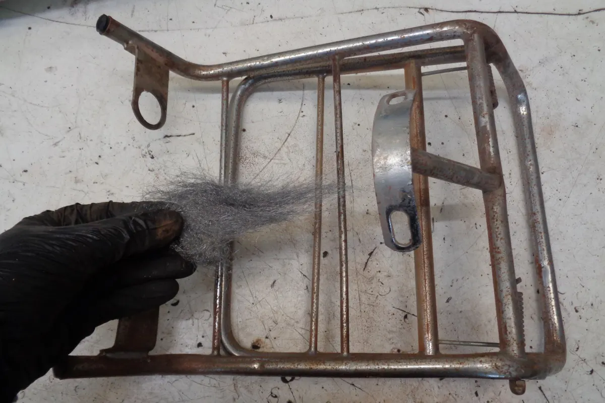 Portabultos de Vespino oxidado sobre una mesa previo a limpiarlo con Lana de Roca