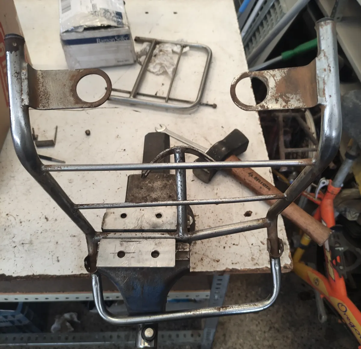 Portabultos de vespino fijo a un torno de mesa en proceso de reparación 