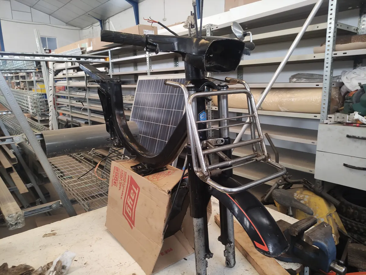 Chasiis y dirección de vespino sobre una mesa en proceso de restauración