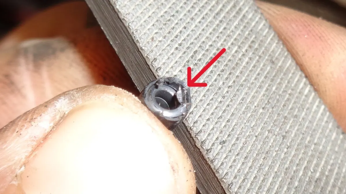 Extremo de una funda de cable mecánico de moto cortado y con una rebaba que se eliminará con la lima que hay tras él.